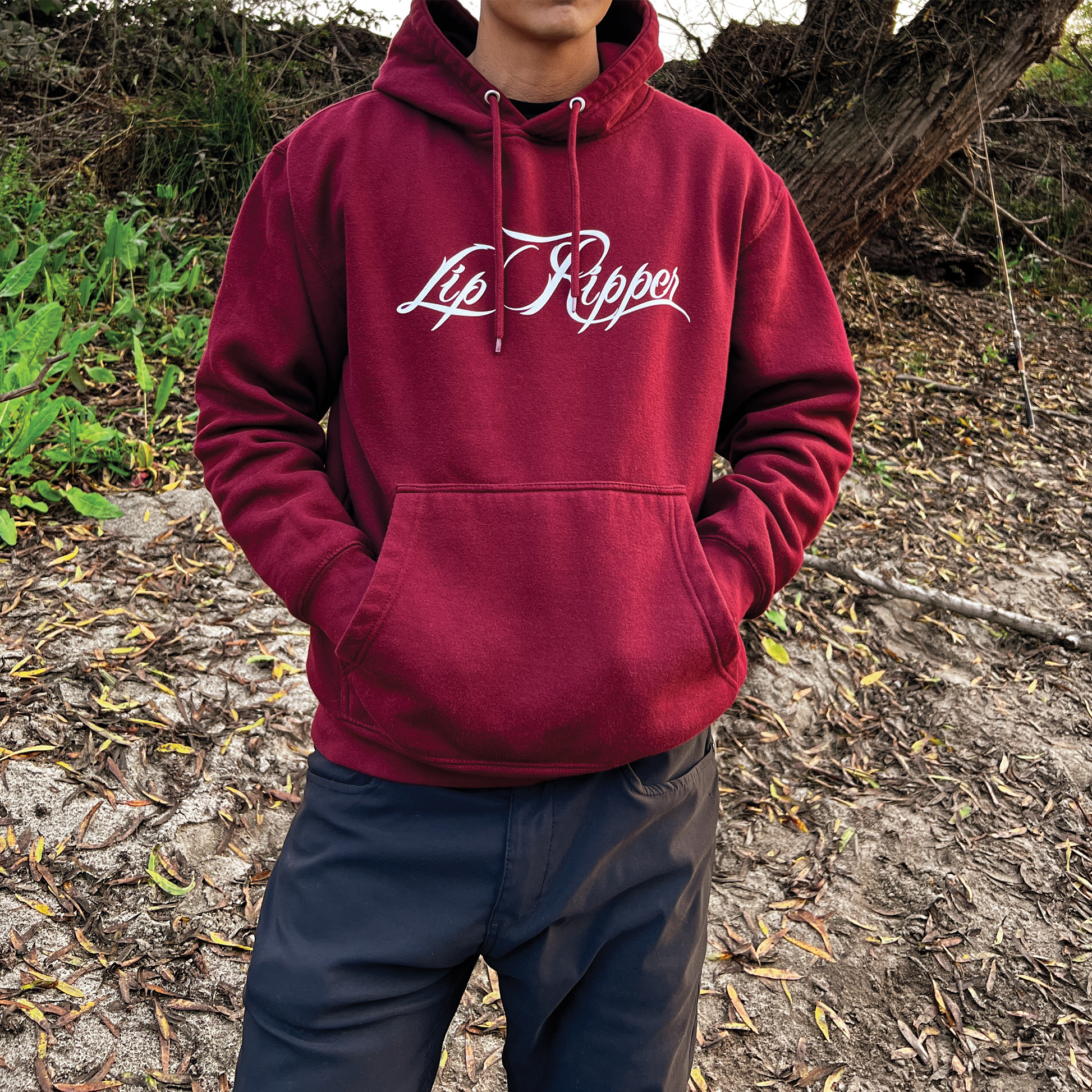 Person with sun glasses on by a river with a burgundy hoodie that says Lip Ripper