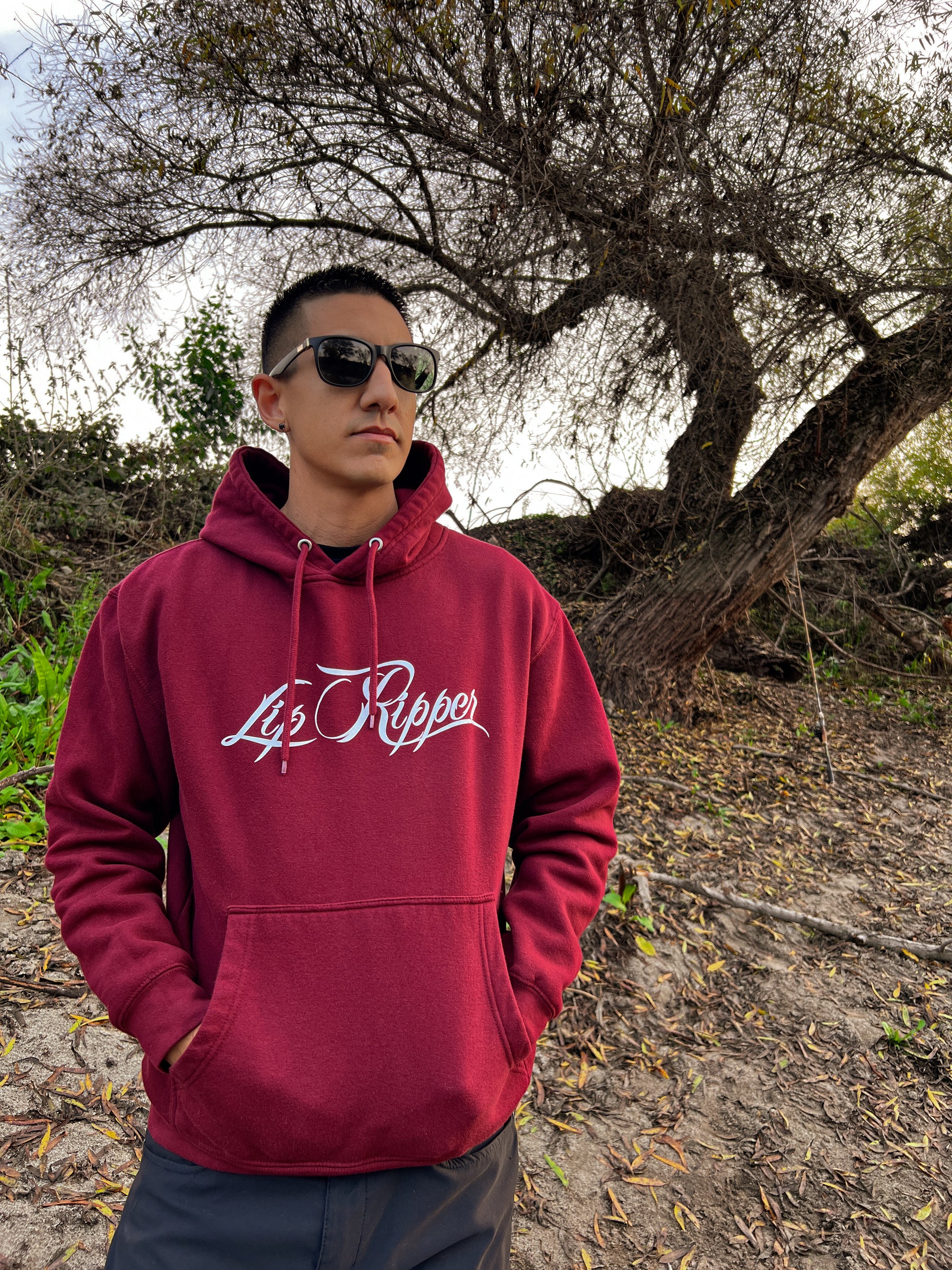 Person with sun glasses on by a river with a burgundy hoodie that says Lip Ripper