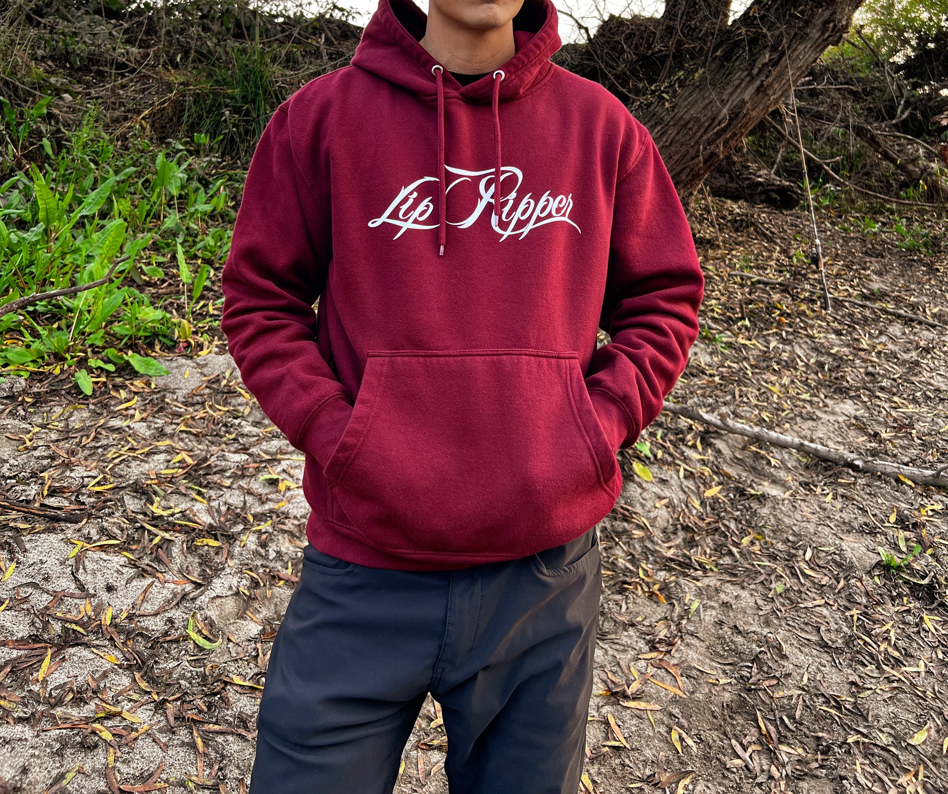 Person with sun glasses on by a river with a burgundy hoodie that says Lip Ripper