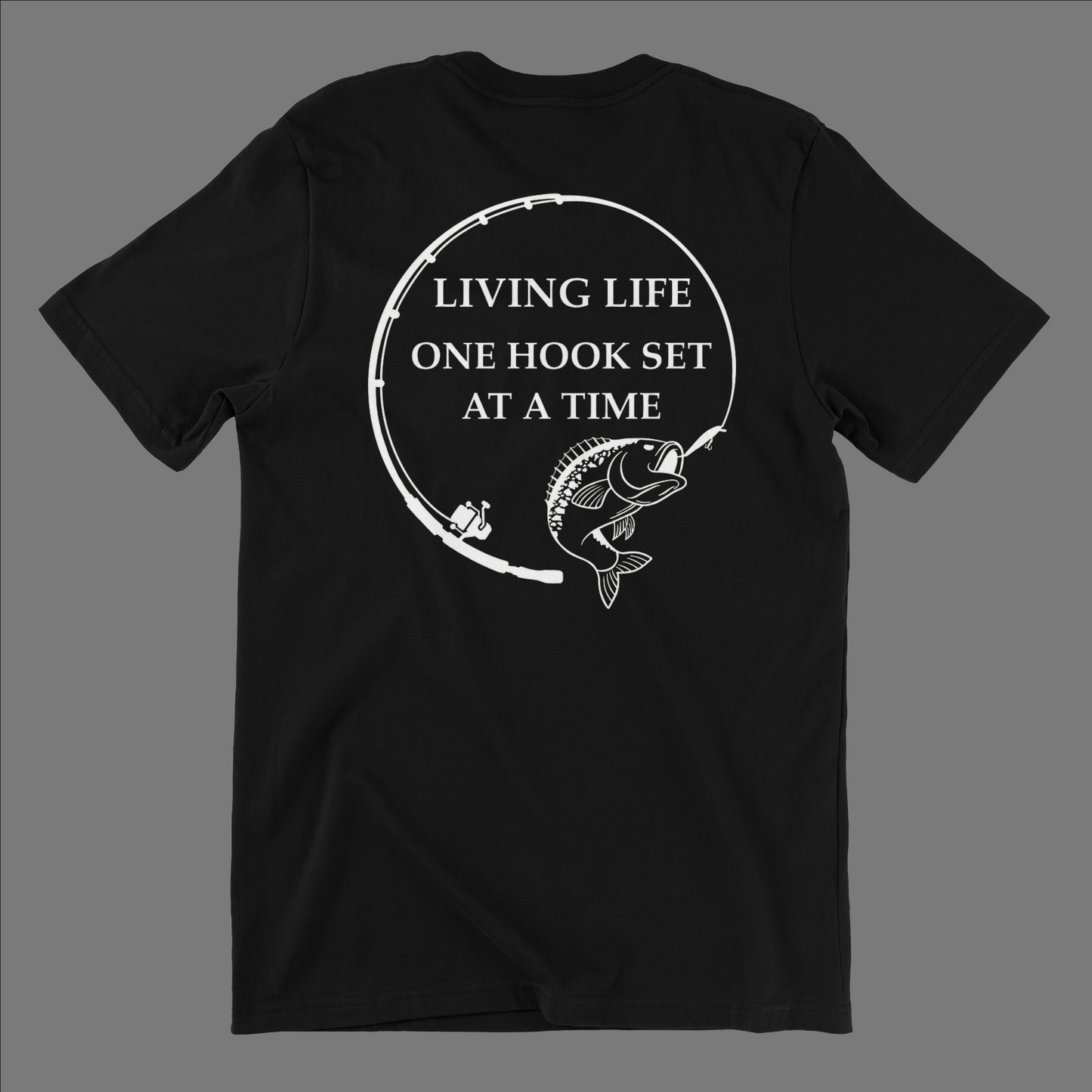 Back side of a black t shirt with a fishing rod bent in a circle and a large mouth bass at the end of it. In the middle of the design it says Living life one hook set at a time in capital letters